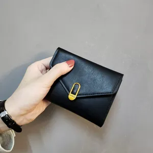Detail view of a black folding short wallet for women with gold metal clasp and card slots.