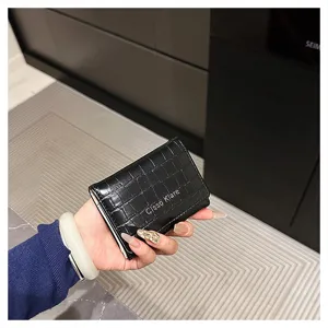 Vue détaillée du portefeuille court noir pour femme motif crocodile avec fermoir métal.