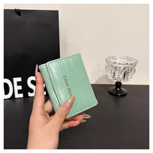 Gros plan d'un petit portefeuille court vert menthe à motif croco avec bouton-pression et fentes.