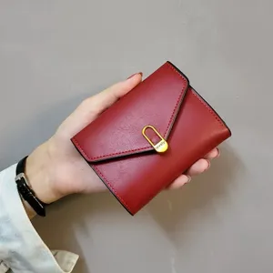 Red leather short wallet, envelope flap design with golden metal buckle detail, close-up view.