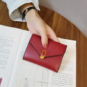 Red short folding wallet detail view, compact leather card holder with gold clasp.