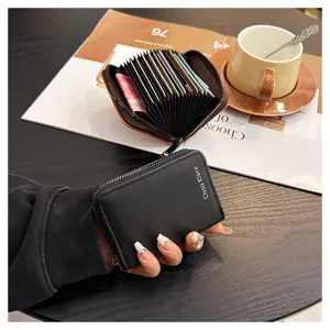 Black leather card holder close-up showing accordion card slots and metal zipper detail.