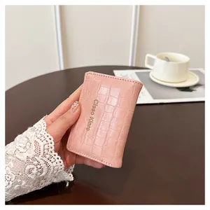Vue détaillée du petit portefeuille rose effet crocodile avec boucle et porte-cartes.