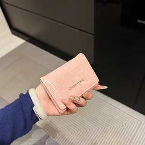 Portefeuille court à motif crocodile rose pour femme avec fermeture métallique et lettre élégante.