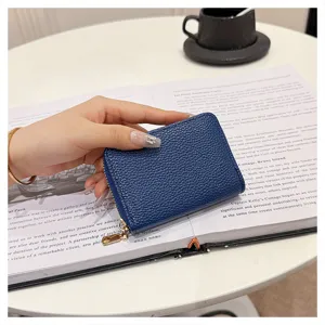 Detalle de tarjetero con cremallera en piel texturizada azul, estuche compacto multi-ranura diario.