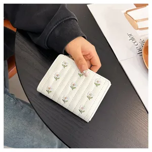 Detailed view of a cute white short wallet featuring delicate daisy embroidery and zipper design.