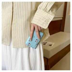 Close-up detail shot of a cute light blue trifold wallet with playful cow print design.