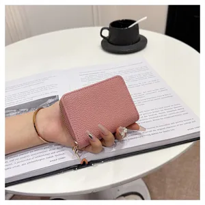 Detalle de tarjetero con cremallera en piel texturizada rosa, cartera compacta con ranuras.