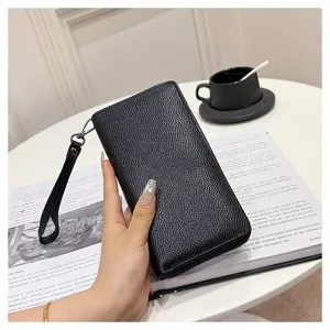 Vista detallada de la cartera larga de piel texturizada negra con correa para la muñeca.