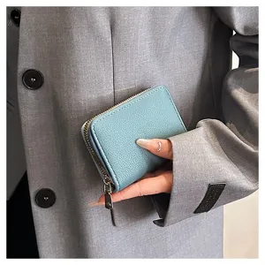 Vue rapprochée détaillée d'un porte-cartes zippé en cuir PU bleu clair tenu à la main.