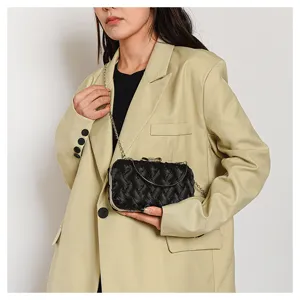 Dettaglio pochette da sera intrecciata nera con tracolla a catena e fiocco elegante.