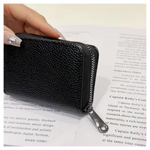 Primer plano del tarjetero monedero de cuero negro con textura granulada y tirador metálico.