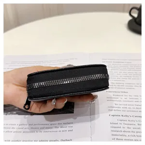 Primer plano detallado del tarjetero de cuero negro con cremallera que muestra su estructura.