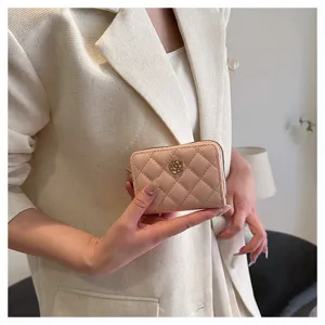 Vista dettagliata di un astuccio trapuntato rosa con fiore di camelia in metallo e zip.