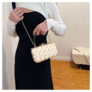 Squisito dettaglio di una borsa da sera intrecciata dorata con manico e catena.