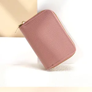 Detail de porte-cartes en cuir rose zippé montrant la texture fine et la taille compacte.