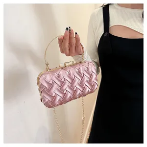 Borsetta da sera a mano intrecciata rosa con manico in metallo tondo e catena elegante.