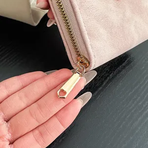 Portafoglio rosa opaco con zip dorata e tiralampo a cuore, vista ravvicinata dell'astuccio.