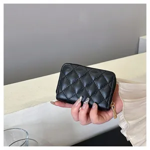 Close-up detail shot of a black quilted card wallet with zipper, showing texture and compact size.