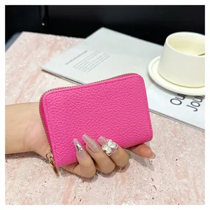 Vista detallada de una cartera tarjetero con cremallera de cuero texturizado rosa.