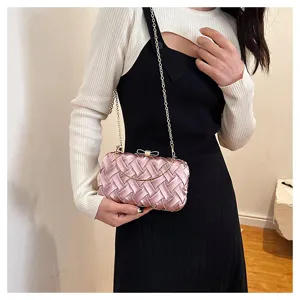 Squisito dettaglio di pochette da sera intrecciata rosa con catena e fiocco elegante.