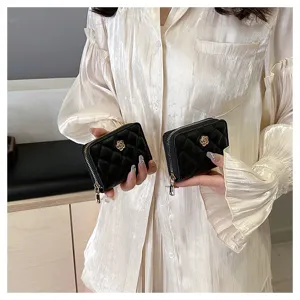Portacarte trapuntato nero mini portamonete con zip e dettaglio di fiore di camelia dorato.