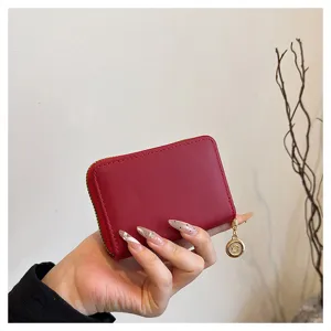Close-up view of a compact red card holder wallet featuring smooth zipper closure and gold pendant.