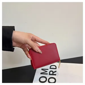 Detailed view of a compact red wallet with metal zipper, showcasing premium leather texture.