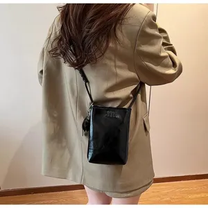 Mini black crossbody phone bag for women, stylish glossy design with strap and cute small charm.
