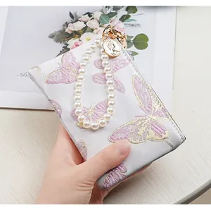 Exquisite butterfly embroidery purse detail, elegant pearl wrist strap, compact card holder.