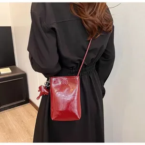 Detail view of mini red leather smartphone crossbody bag with cute elephant charm.