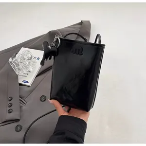 Black glossy mini phone bag with cute elephant pendant, stylish crossbody accessory for women.