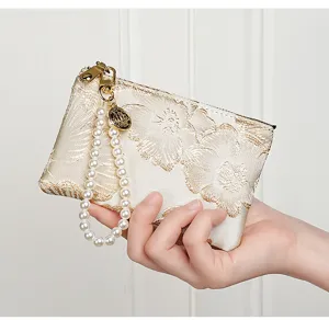 Close-up detail of Chinese style embroidered coin purse with elegant pearl wrist strap.