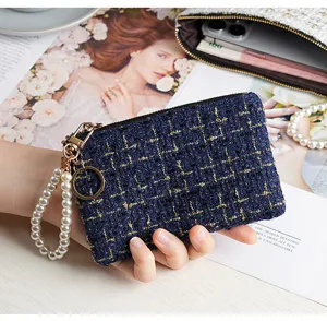 Chic dark blue tweed coin purse featuring pearl wrist strap and premium gold hardware.