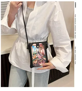 Detailed view of women's black crossbody phone bag with cute anime illustration print.