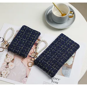 Detailed view of dark blue tweed card pouch with pearl wrist strap and gold accents.