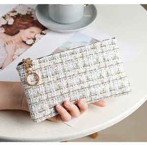 Tweed zip coin pouch with gold ring pull, compact wallet detail on white table setup.
