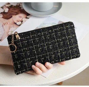 Close-up of black tweed zipper wallet detail showing gold threads and metal ring accessory.