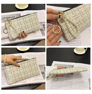 Chic tweed coin purse with pearl wrist strap and zipper, elegant mini clutch bag for women.