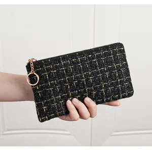 Detailed view of the black and gold tweed zipper pouch with metallic ring and chain accent.