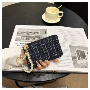 Detailed shot of tweed coin purse with pearl wrist strap and gold zipper closure in chic cafe scene.