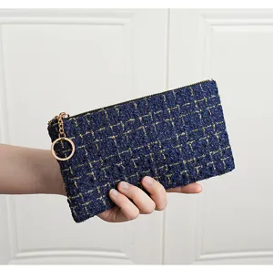 Detail shot of a dark blue tweed coin purse with gold metallic threads and keyring.