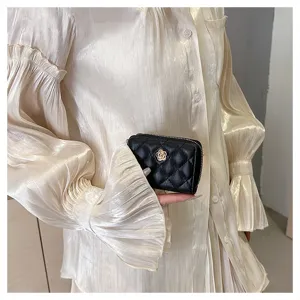 Portafoglio porta carte trapuntato nero con elegante emblema di camelia dorata e chiusura zip.