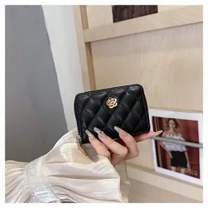 Primo piano dettagliato del portacarte trapuntato nero con un raffinato camelia dorata.