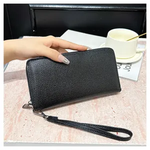 Cartera larga de cuero texturizado negro con correa de muñeca, vista de detalle elegante.