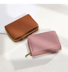 Gros plan de porte-cartes compacts en cuir à fermeture éclair, marron et rose, avec détails dorés.