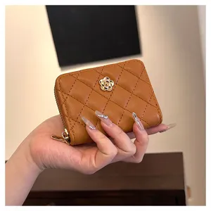 Primo piano del porta carte trapuntato marrone con emblema di fiore di camelia d'oro.
