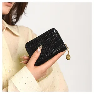 Detailed close-up shot of the black crocodile pattern mini wallet, showing texture and zipper pull.