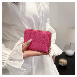 Mini cartera de cuero rosa monedero tarjetero sostenido en mano con diseño compacto con cierre.