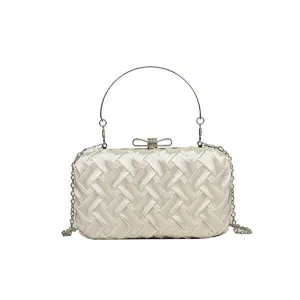 Elegante borsa da sera intrecciata con manico in metallo, fiocco in strass e tracolla.